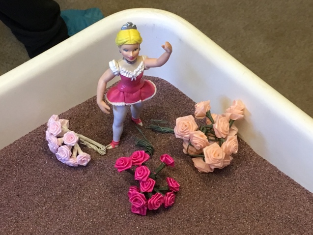 A toy ballerina in a box with flowers