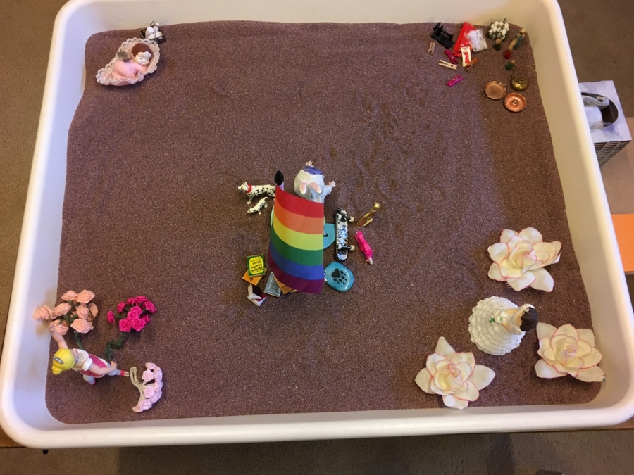 A tray with a rainbow colored sand and toys